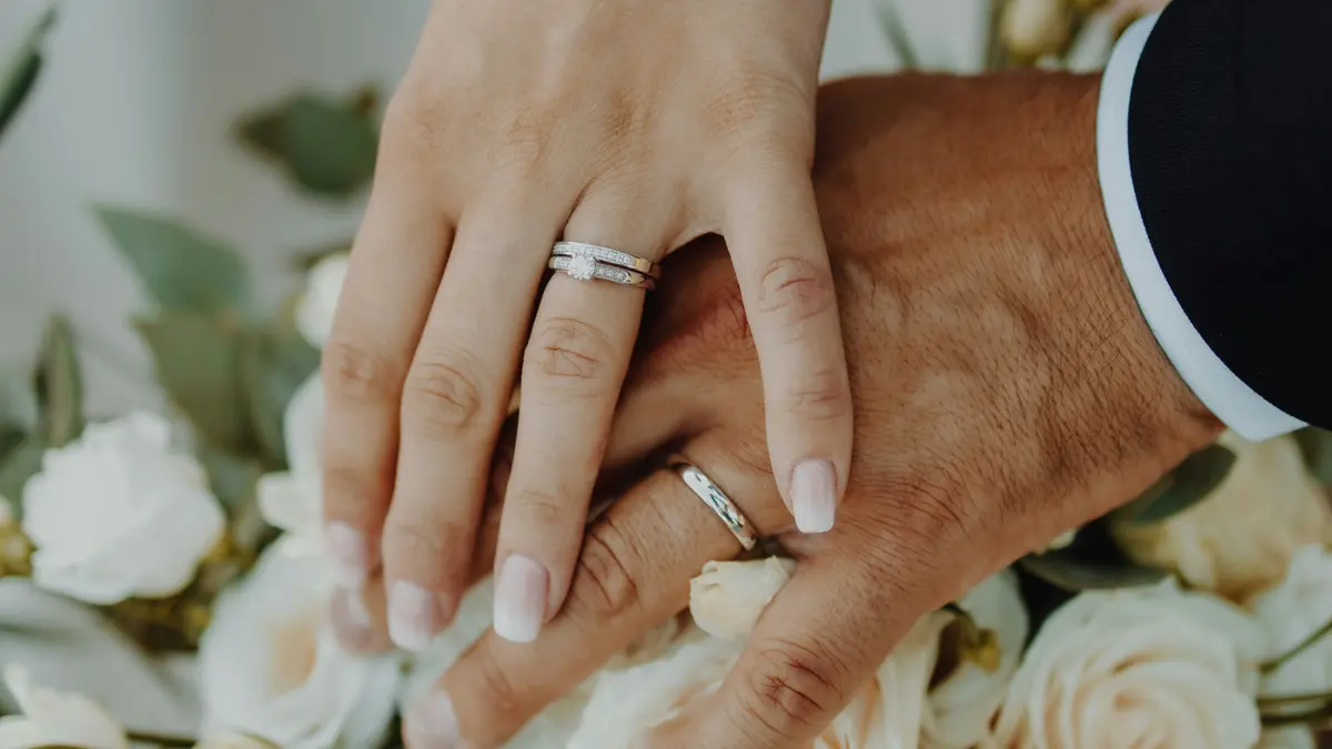 Manos de novios con alianzas de boda sobre ramo de flores en Bilbao